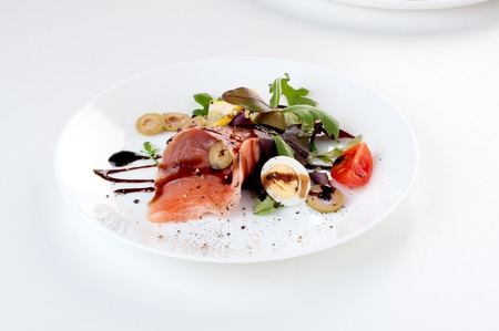salmon salad greens olives lemon balsamic sauce on a white backgroundの写真素材