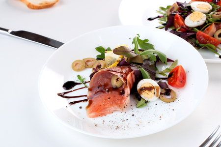 salmon salad greens olives lemon balsamic on a white backgroundの写真素材