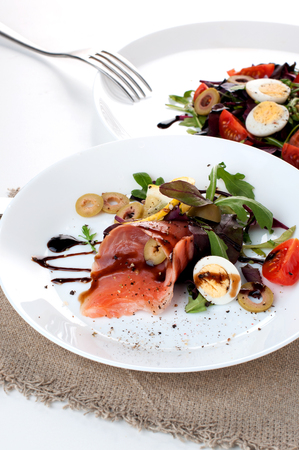 salmon salad greens olives balsamic sauce on a white backgroundの写真素材