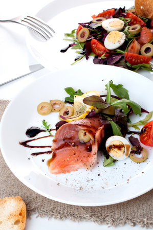 salmon salad greens olives lemon sauce on a white backgroundの写真素材