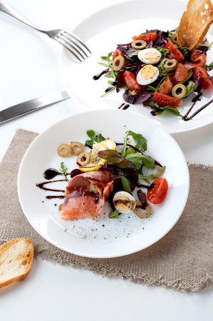 salmon salad tomato olives lemon balsamic sauce on a white backgroundの写真素材