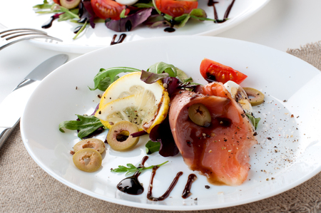 salmon salad greens olives lemon white plate on a white backgroundの写真素材