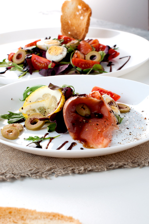 salmon salad greens white plate lemon sauce on a white backgroundの写真素材