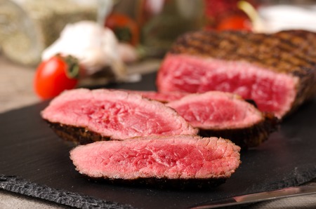 premium beef steak sliced black plate on a gray wooden backgroundの写真素材