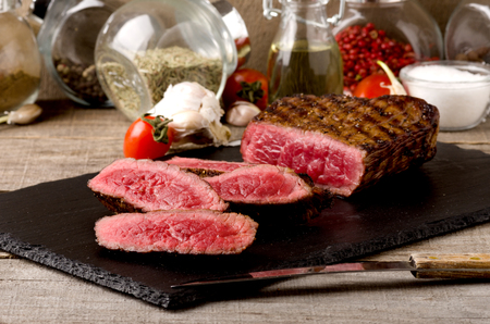 black angus rare steak sliced dark plate on a gray wooden backgroundの写真素材