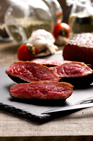 black angus rare steak sliced dark plate on a gray wooden backgroundの写真素材