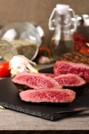 premium beef rare steak sliced black plate on a gray wooden backgroundの写真素材