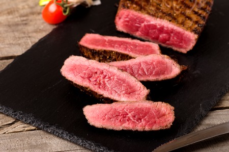 premium beef rare steak sliced on a gray wooden backgroundの写真素材