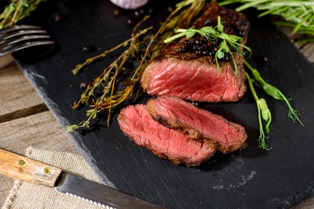 chopped rare bbq steak black angus on black rectangular plate with pea sprout thyme rosemary spiceの写真素材