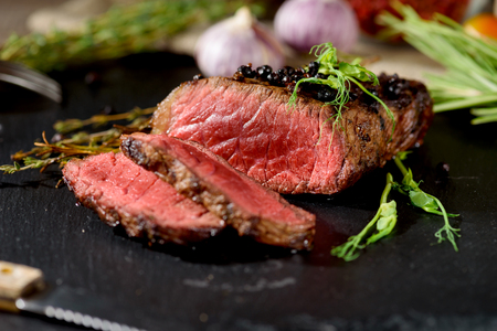 rare steak black rectangular plate pepper on black rectangular plate with pea sprout thyme rosemary spiceの写真素材