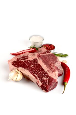 raw t-bone steak pepper salt rosemary garlic shadow on white backgroundの写真素材