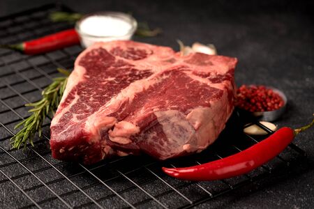 raw beef steak Porterhouse salt rosemary pepper on a dark backgroundの写真素材