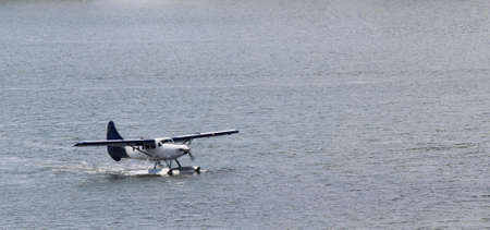 A blue and white float plane taxis out into the bay