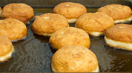 Tasty fat donuts are fried in oil