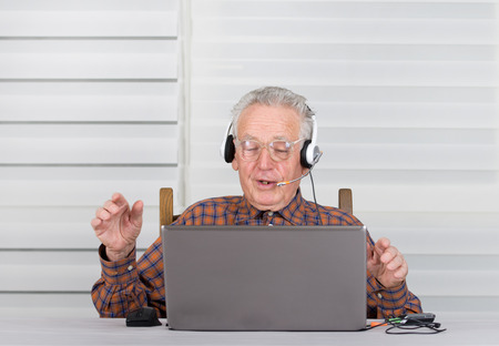 Senior man raised hands up and listen music from laptop