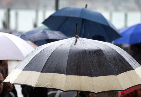 Rainy day and wet umbrellas in crowded streetの写真素材