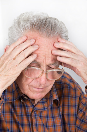 Old man holding hands on forehead and is focused on readingの写真素材
