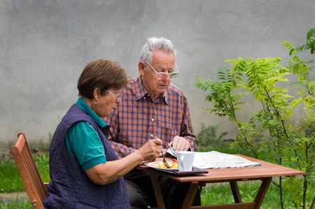 Senior couple sitting in garden in morningの写真素材