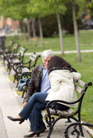 Older couple in hug sitting on bench in parkの写真素材