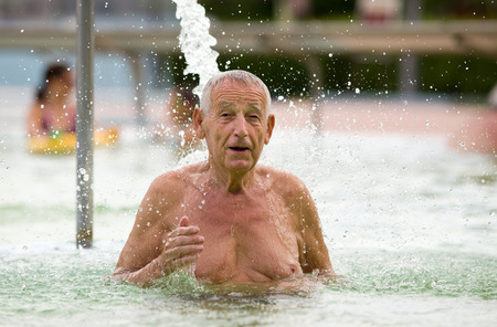 Senior man enjoying waterfall in hot water poolの写真素材