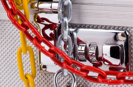 Close up of metallic suitcase with safety code and colored chains around itの写真素材