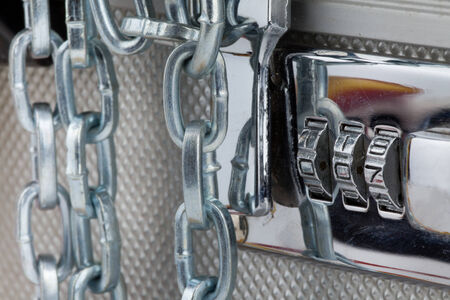 Close up of metallic suitcase with safety code and chains around itの写真素材