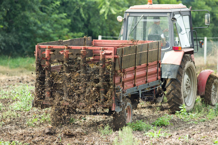 Tractor with trailer fertilizing field with natural manureの写真素材