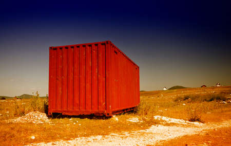 Red used shipping container places in field