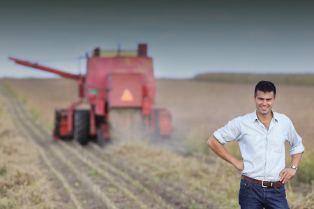 Young satisfied landowner supervising soybean harvesting workの写真素材