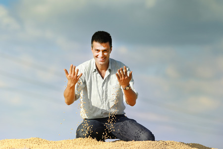 Young satisfied businessman sitting on soybeans heapの写真素材