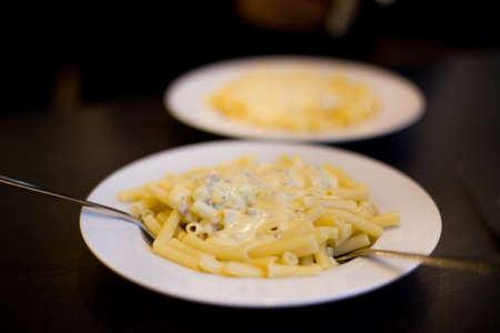 Two plates with macaroni and sauce on dark backgroundの写真素材