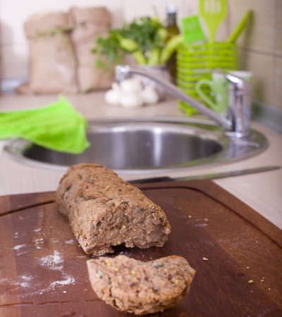 Cut loaf of homemade wholemeal bread on wooden board on kitchen counterの写真素材