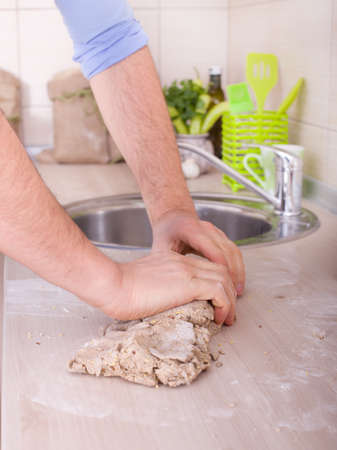 Male hand kneading dough of wholemeal bread on kitchen counter