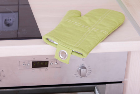 Green heat protective glove on kitchen countertopの写真素材