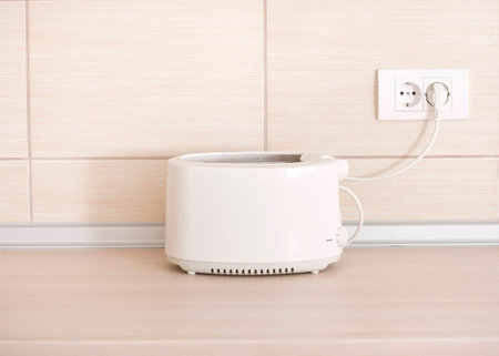 White toaster plugged in socket on kitchen countertop