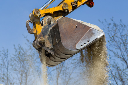 Close up of excavator bucket scooping gravel from pile for road constructionの写真素材