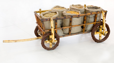 Different grains in sacks arranged in wooden cart on white backgroundの写真素材