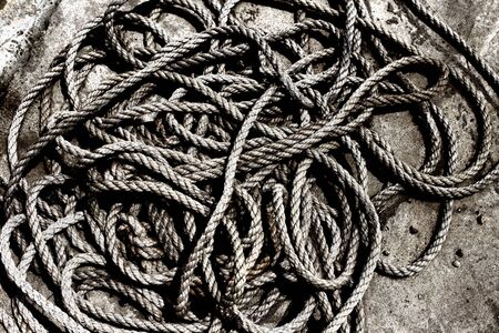 Black and white image of old rope pile on concrete floor