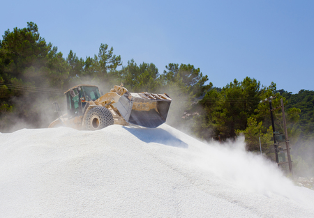 Bulldozer working on the top of huge pile of marble pebble on Thassos in Greece
