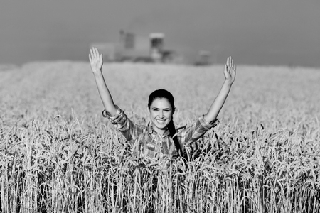 Happy young woman standing in ripe wheat field during harvest, black and white imageの写真素材