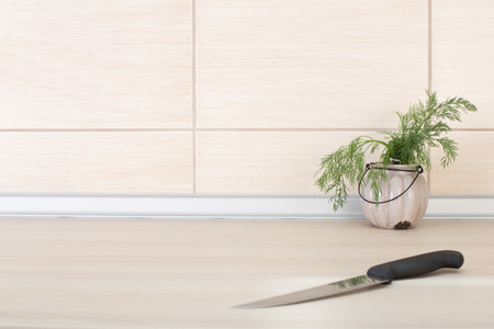 Close up of knife and dill in a pot on wooden countertop in the kitchenの写真素材