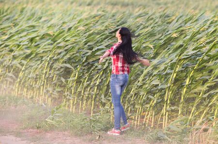 Young girl with black long hair standing in the wind with open armsの写真素材