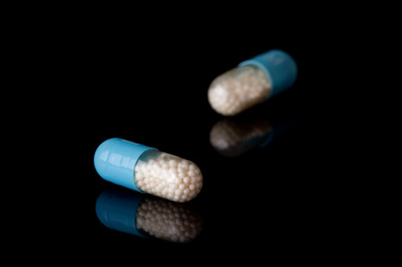 Two capsules on black background with reflectionの写真素材
