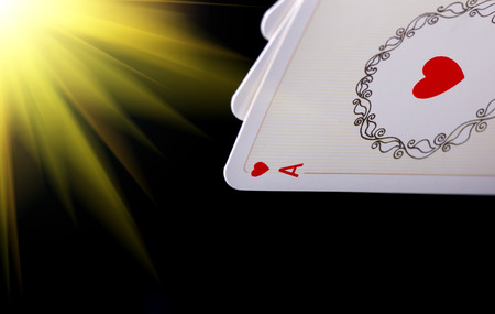 Close up of heart ace in poker hand against  black background with abstract sun rays