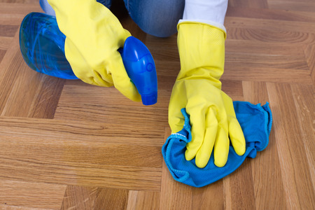 Close up of female hands with rubber gloves cleaning parquet with detergent and clothの写真素材