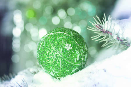 Christmas decoration ball on snowy fir branch on green backgroundの写真素材