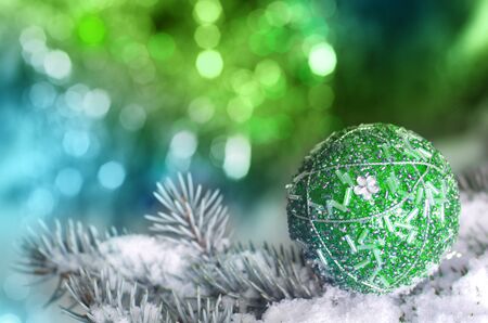 Christmas decoration ball on snowy fir brench on green and blue backgroundの写真素材