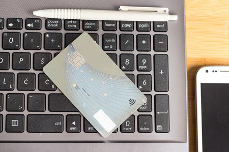 Credit card on the laptop on home desk. E-banking concept