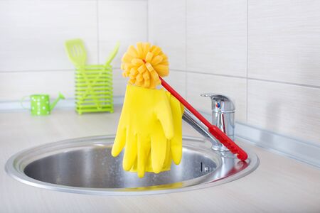 Kitchen cleaning tools. Sponge brush and safety gloves on faucet on the countertopの写真素材