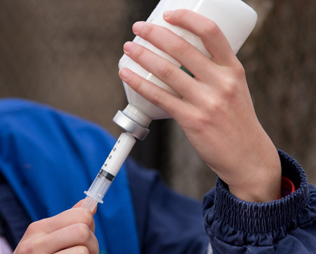 Veterinarian holding syringe with medication on the farmの写真素材